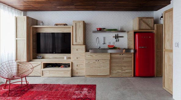 modernes wohnesszimmer mit wohnwand und Küchenzeile aus holz mit rotem smeg kühlschrank und teppich